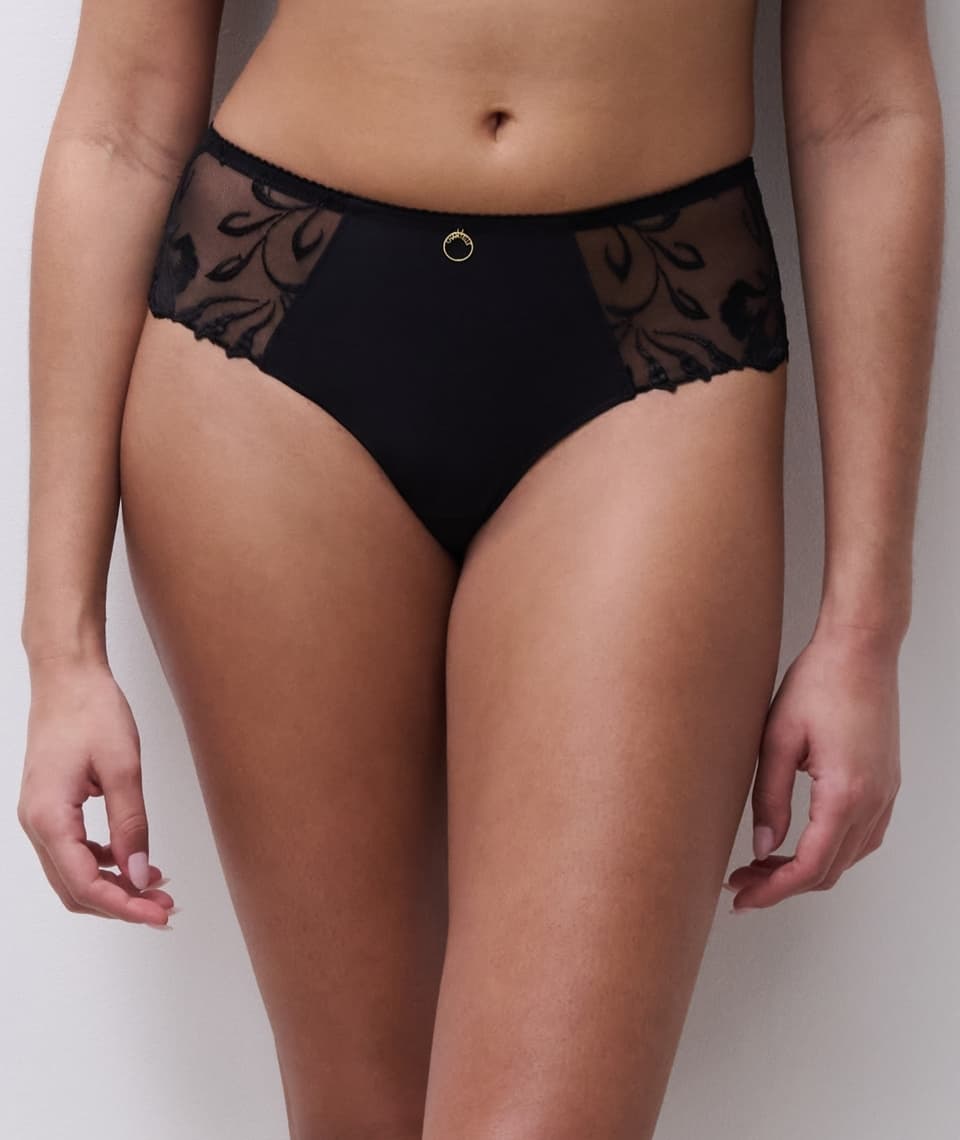 Person wearing black high-waisted panties with sheer floral lace panels and a small gold emblem at the waist.