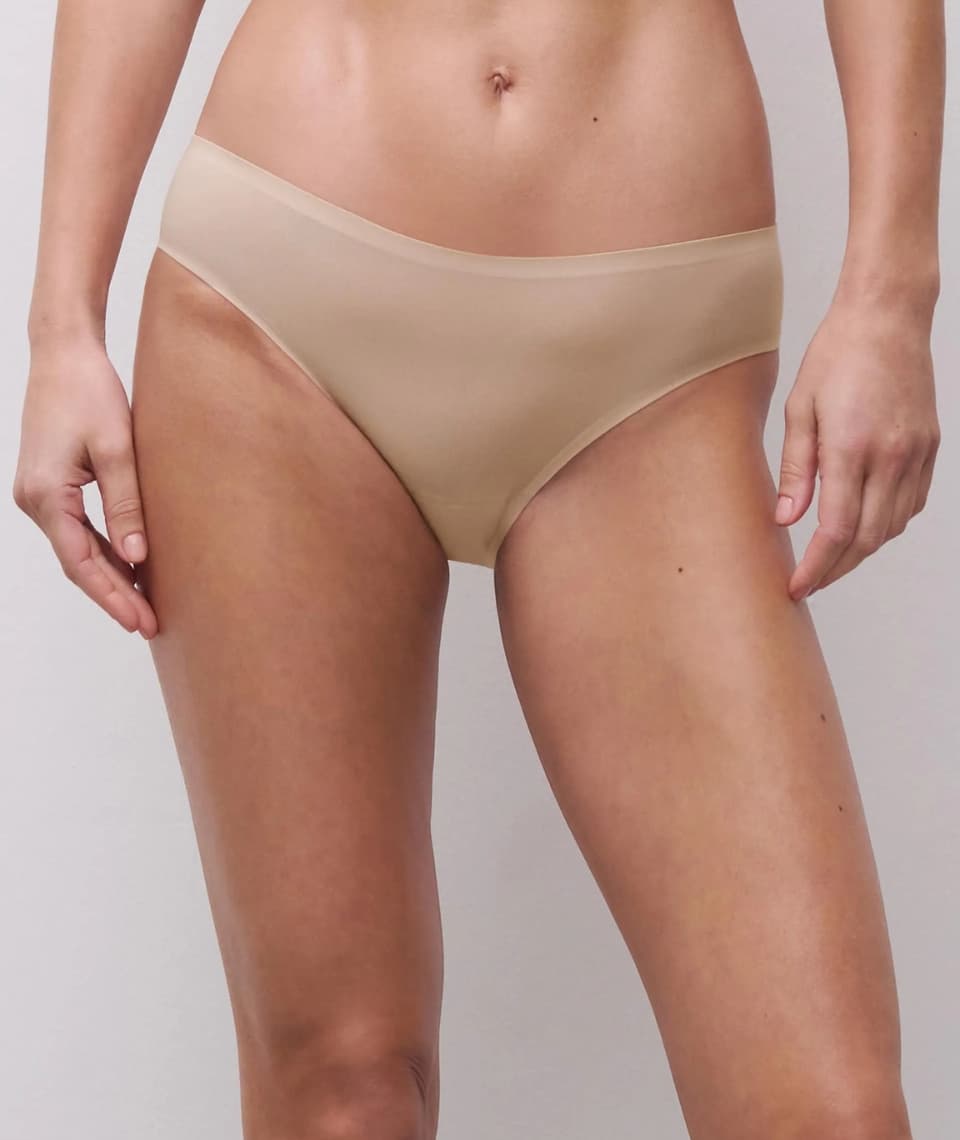 Close-up of a person wearing seamless, golden beige-colored underwear with a smooth finish against a neutral background.
