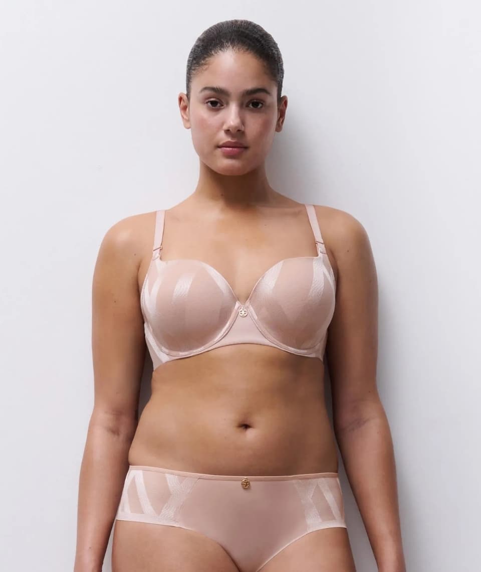 Person wearing a matching soft pink lingerie set, standing against a plain white background.