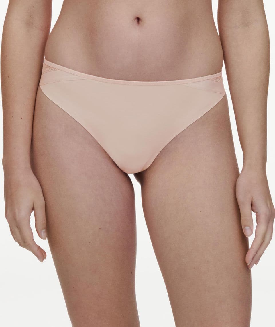 A person wearing seamless, nude-colored panties, showing a front view from the waist to mid-thigh against a white background.