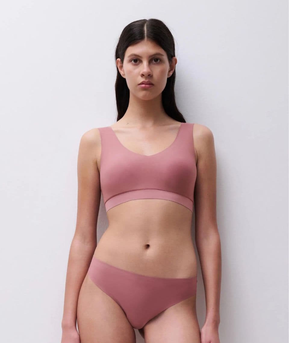 Woman wearing a matching dusty rose bralette and underwear, standing against a plain white background.