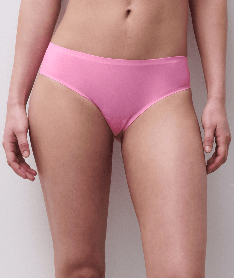 Person wearing pink bikini-style underwear against a plain background.