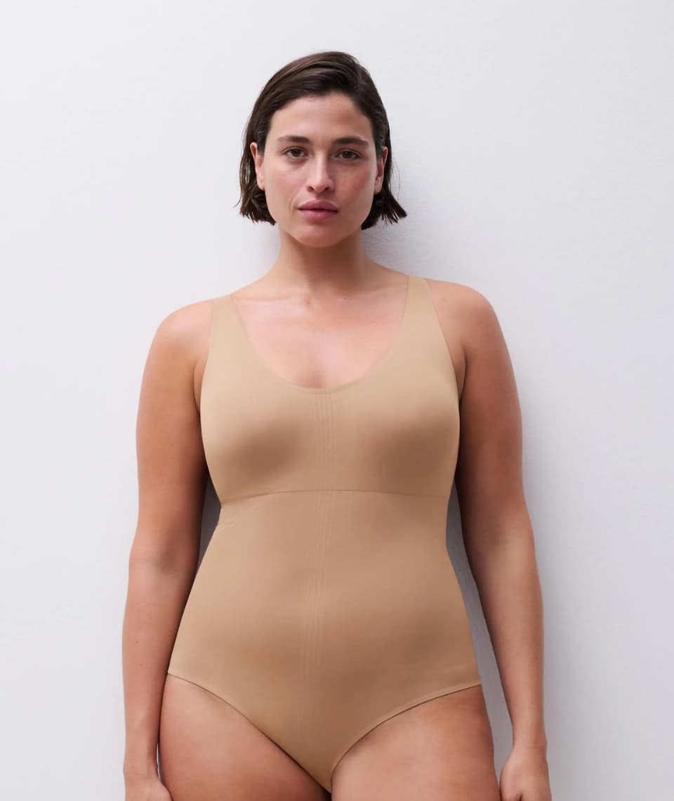 Person wearing  shapewear and standing against a plain white background.