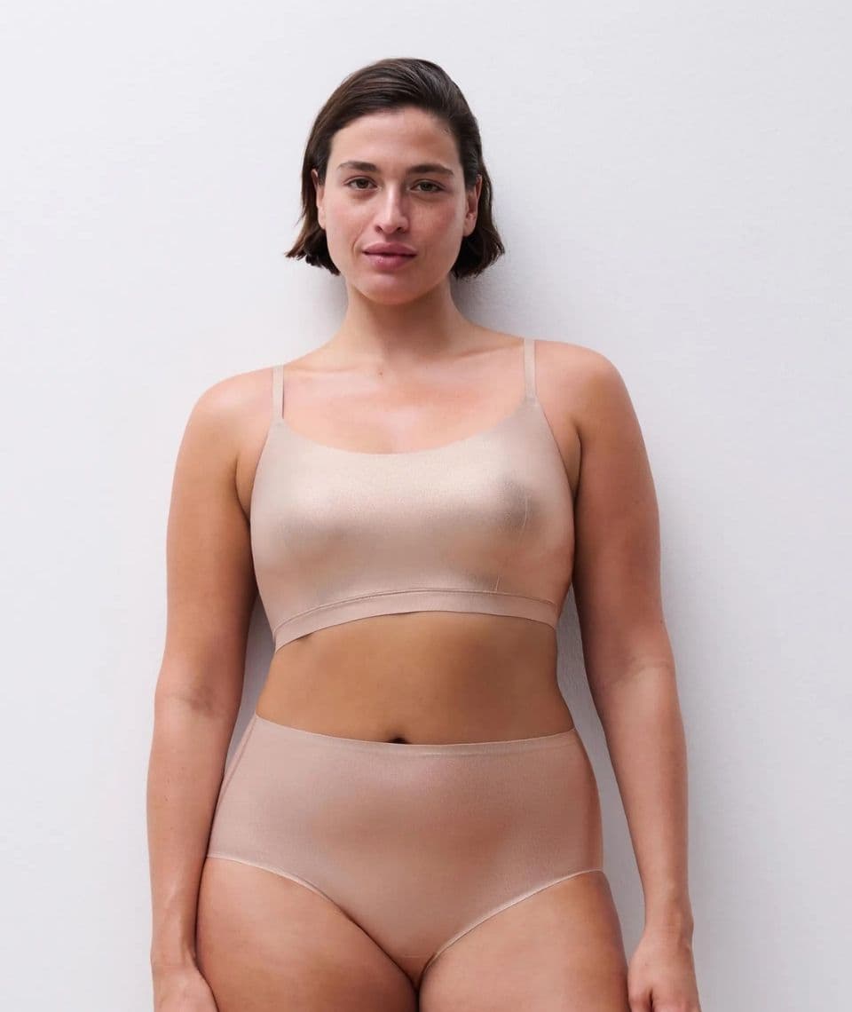 Person wearing golden glow colored underwear, including a sleeveless top and high-waisted bottoms, standing against a plain white background.