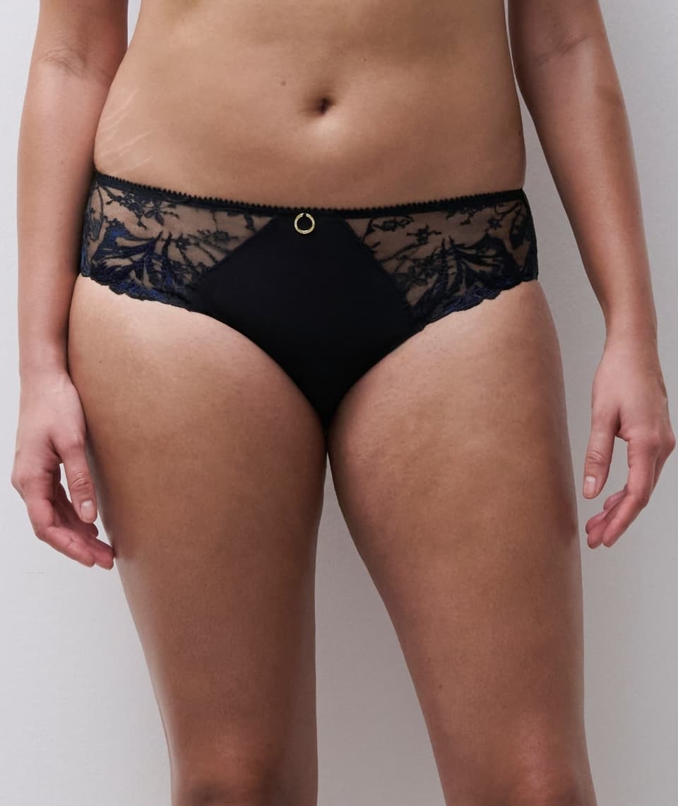 A person wearing black lace panties with a subtle floral design.