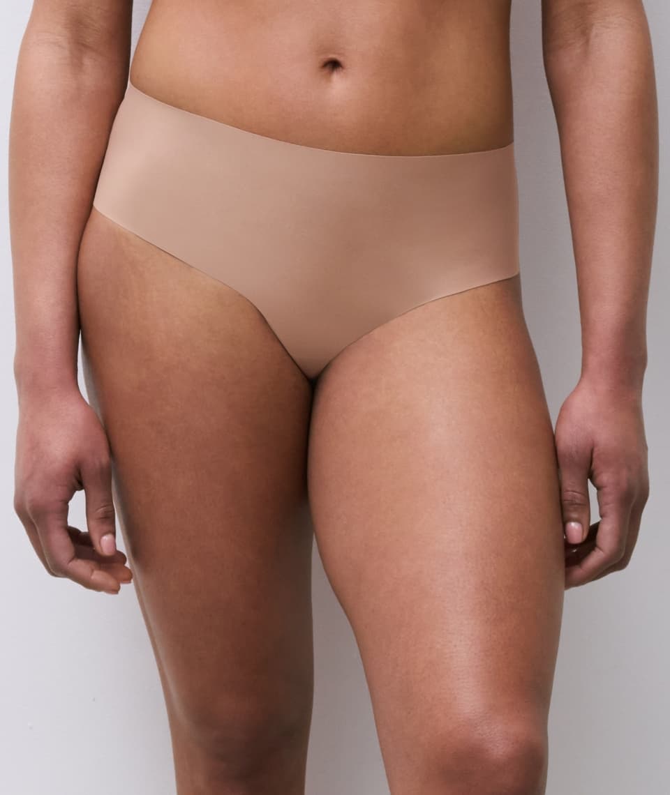 Person wearing seamless, coffeelatte-colored underwear standing against a plain background.