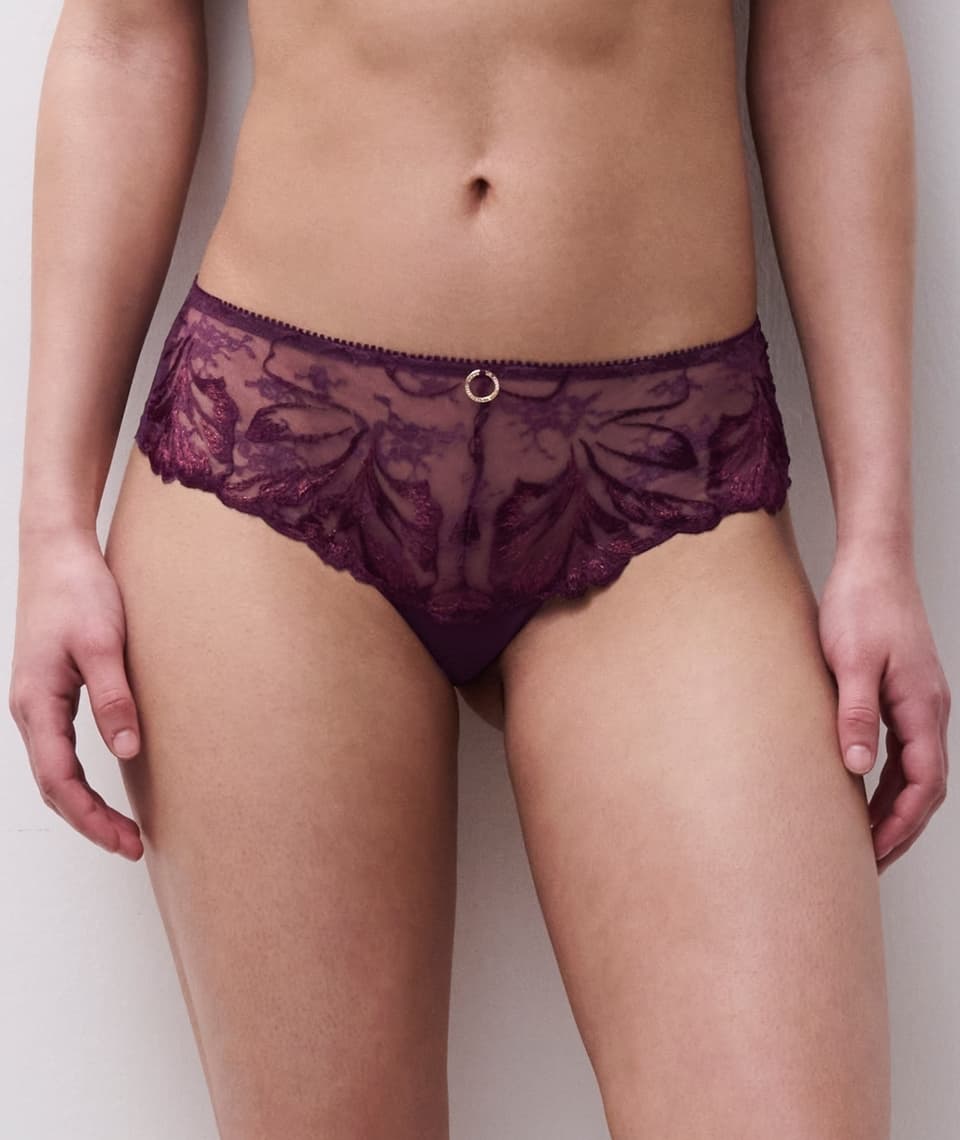 Person wearing a dark lace panties with floral patterns, featuring a small decorative ring at the center waistband.