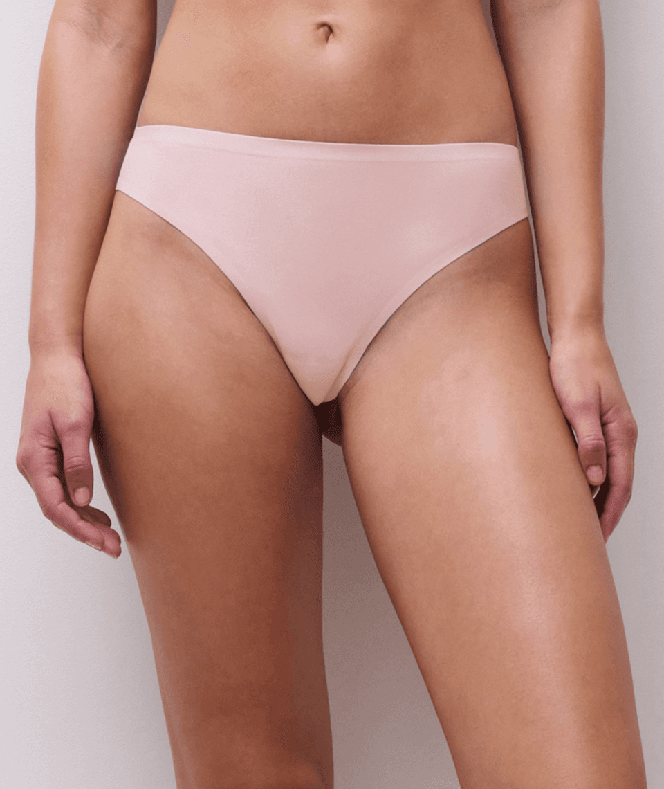 A person wearing light pink seamless underwear standing against a neutral background.