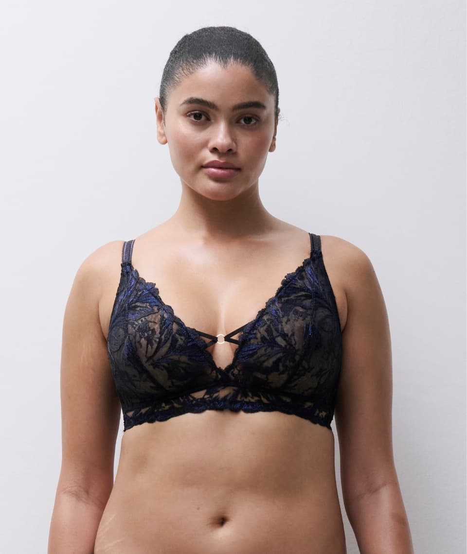 Person wearing a dark lace bralette, standing against a plain background.