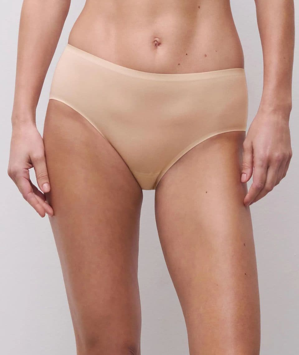 Person wearing seamless beige underwear bottoms, standing against a light gray background. Hands relaxed by their sides.