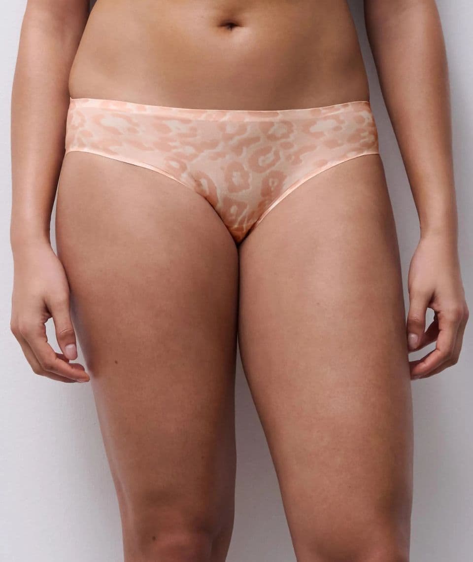 Person wearing light leopard print panties against a plain background.