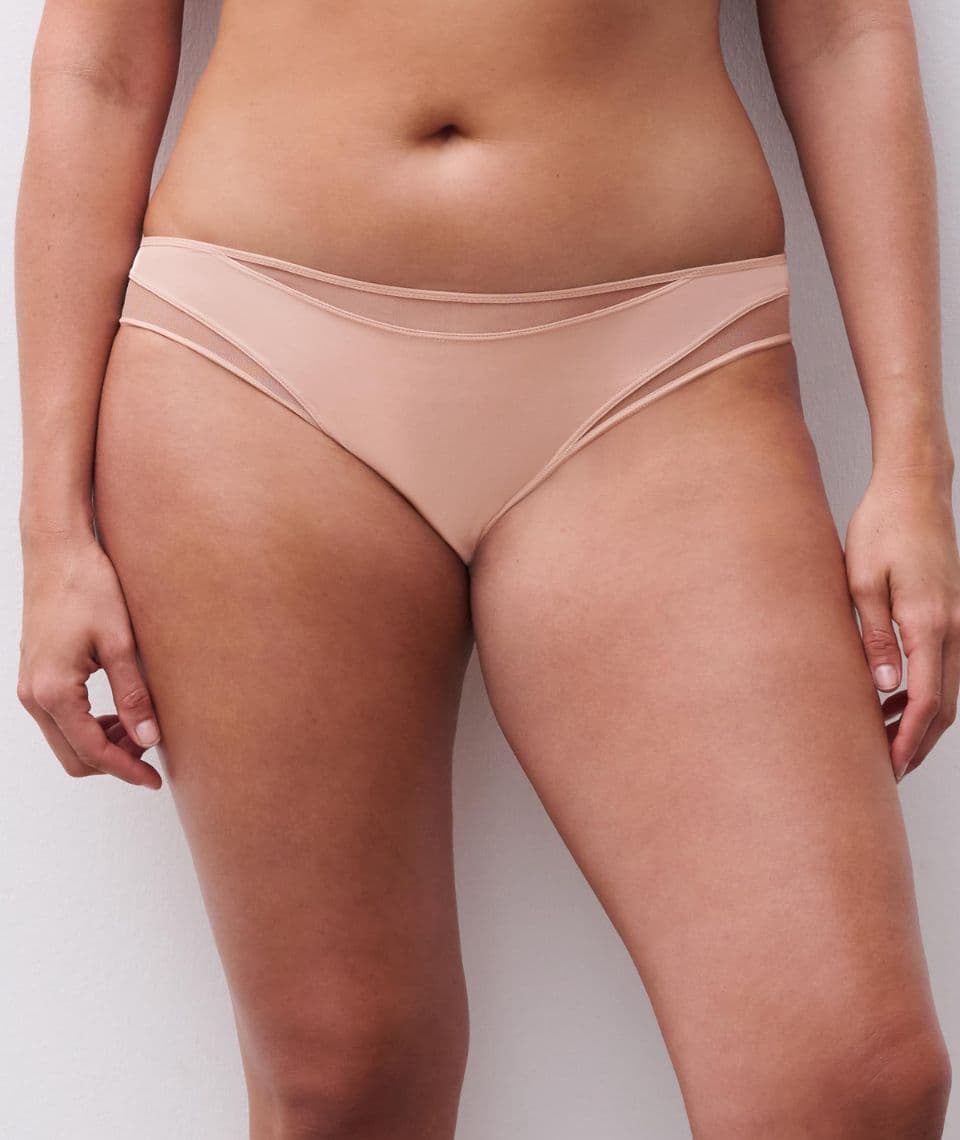 A person wearing beige underwear stands against a plain white background. The focus is on the midsection and underwear design.