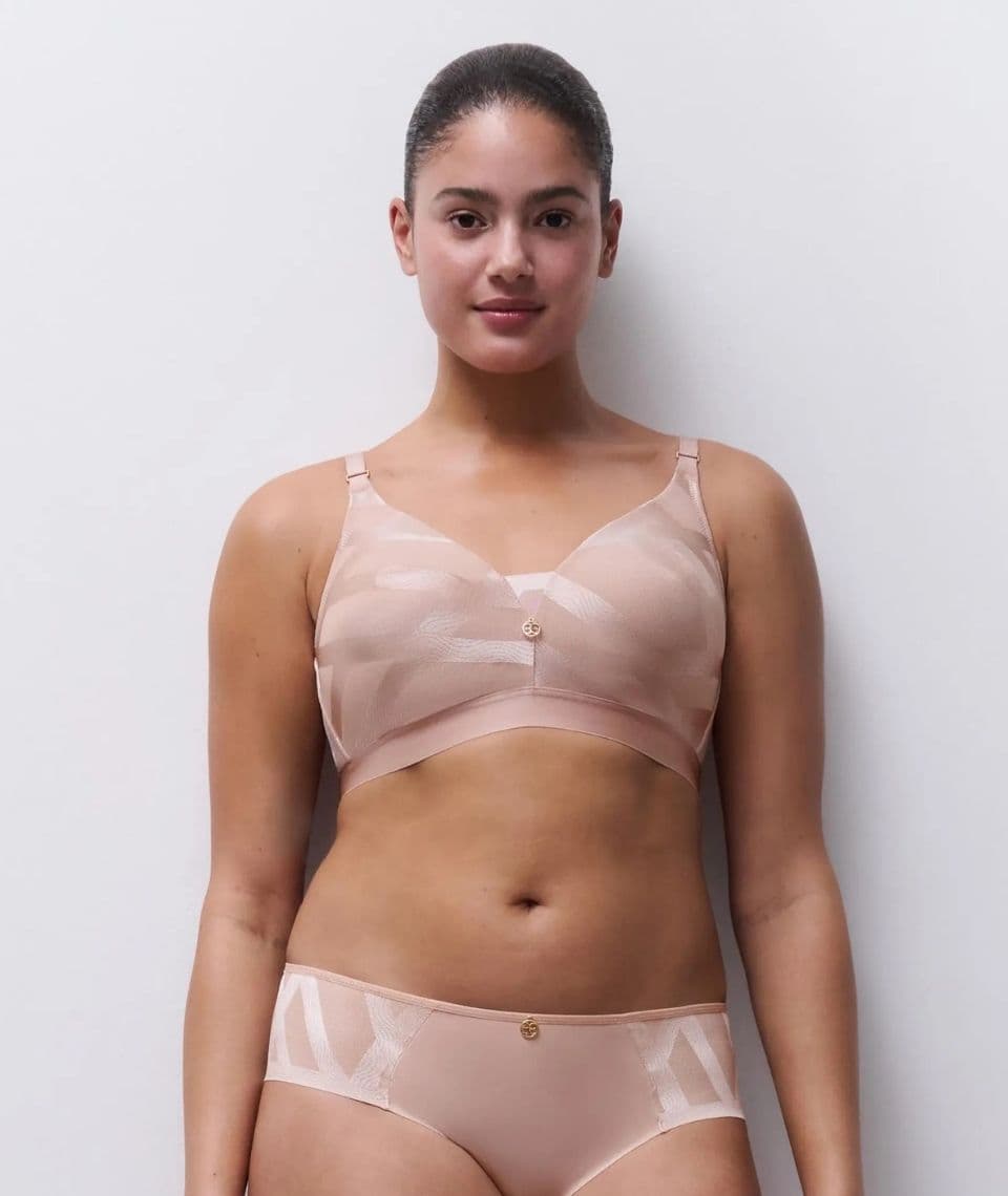 Person wearing a matching set of light pink lingerie, standing against a plain white background.