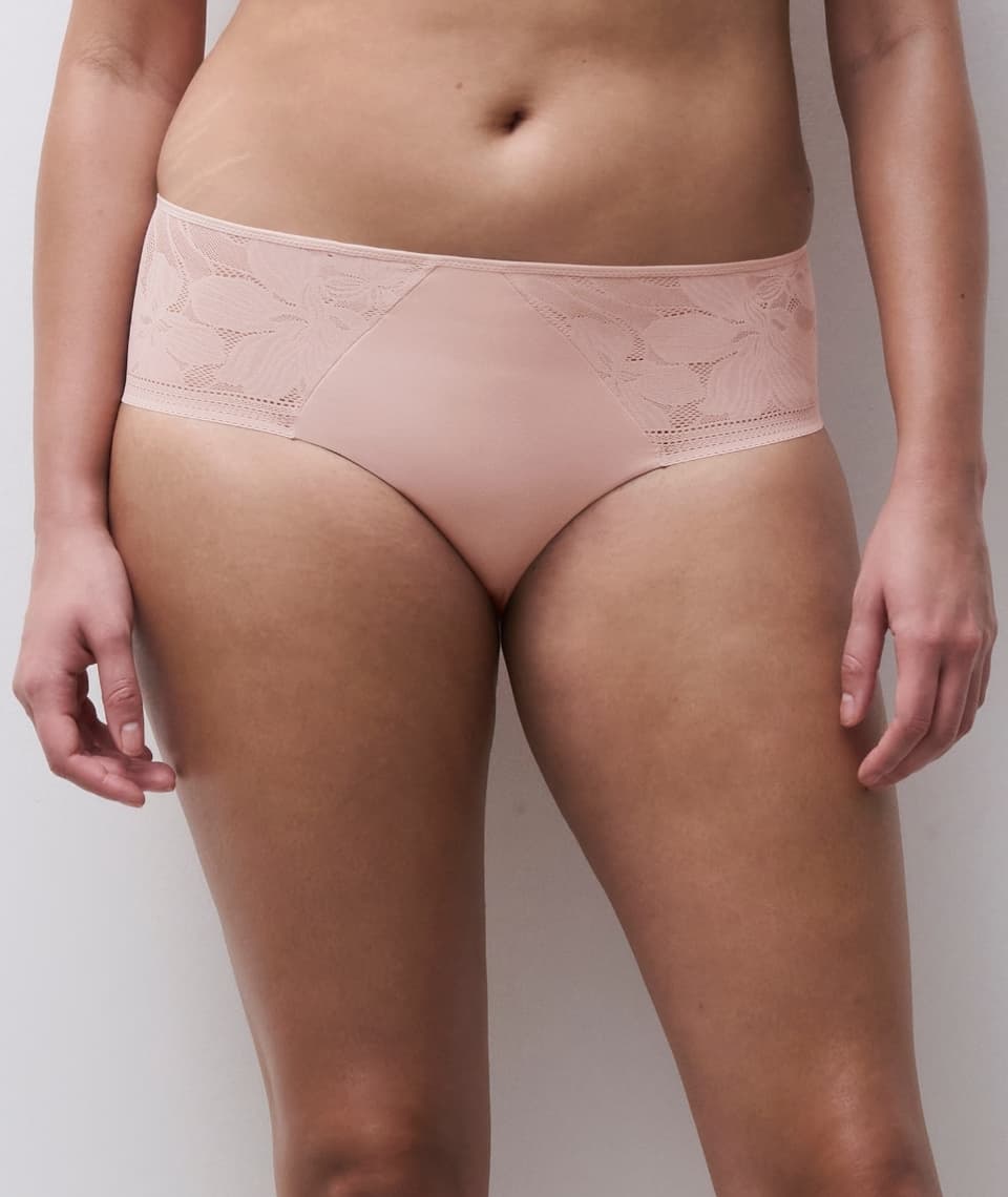 A person wearing light pink lace hipster panties, showing a partial view of their torso and thighs against a neutral background.