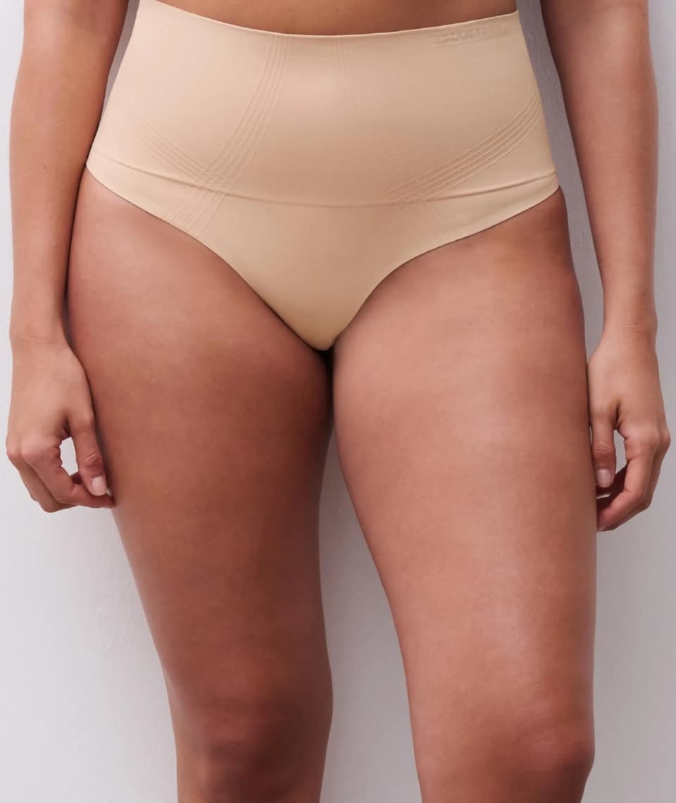 A person wearing beige high-waisted shapewear briefs, standing against a plain background.