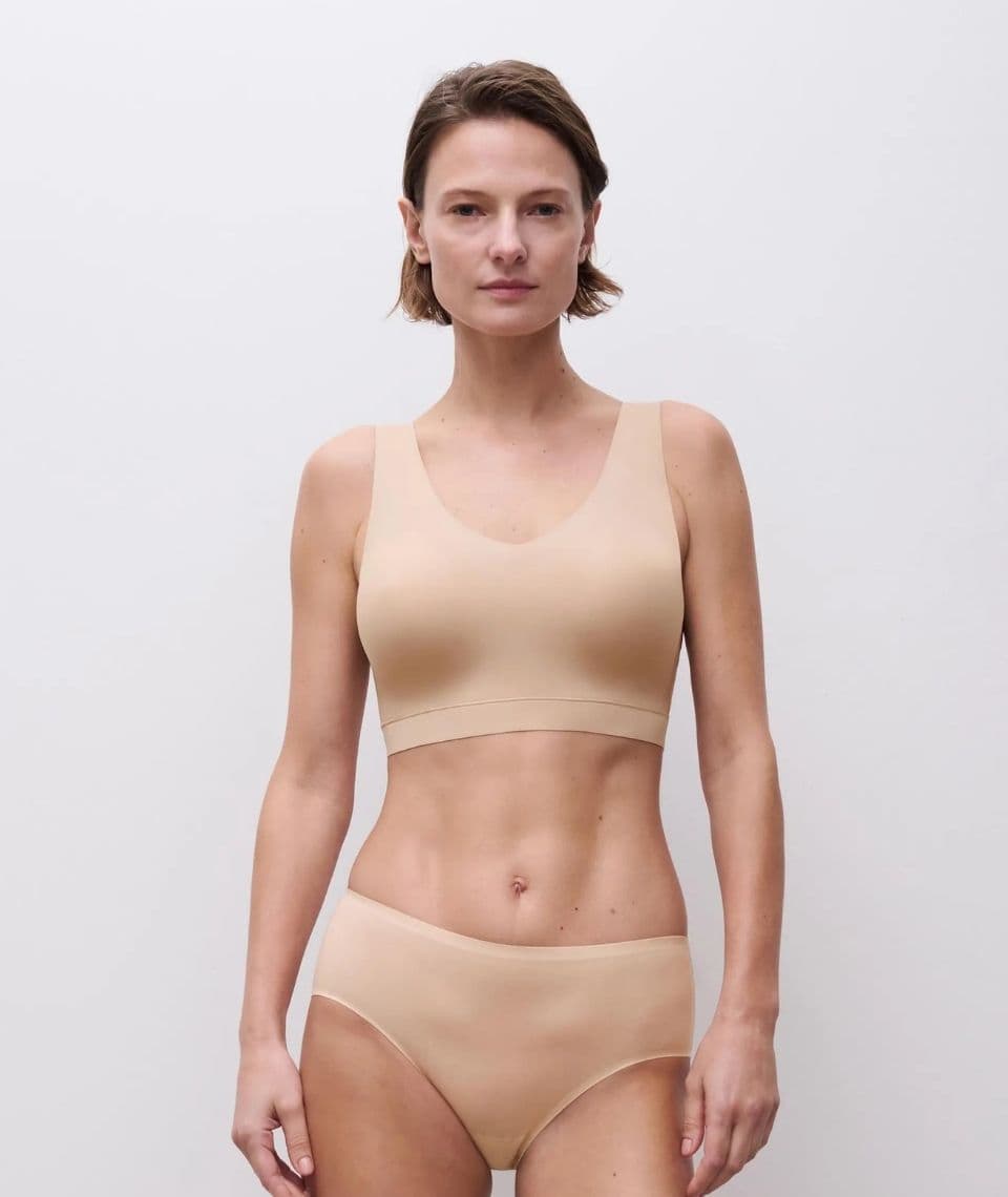 A person in a nude seamless underwear stands against a plain white background.