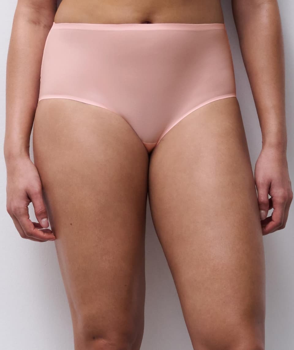 Person wearing high-waisted, light pink underwear, standing against a neutral background.