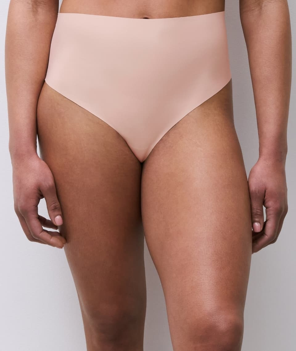 Close-up of a person wearing high-waisted, light beige seamless underwear, standing against a neutral background.