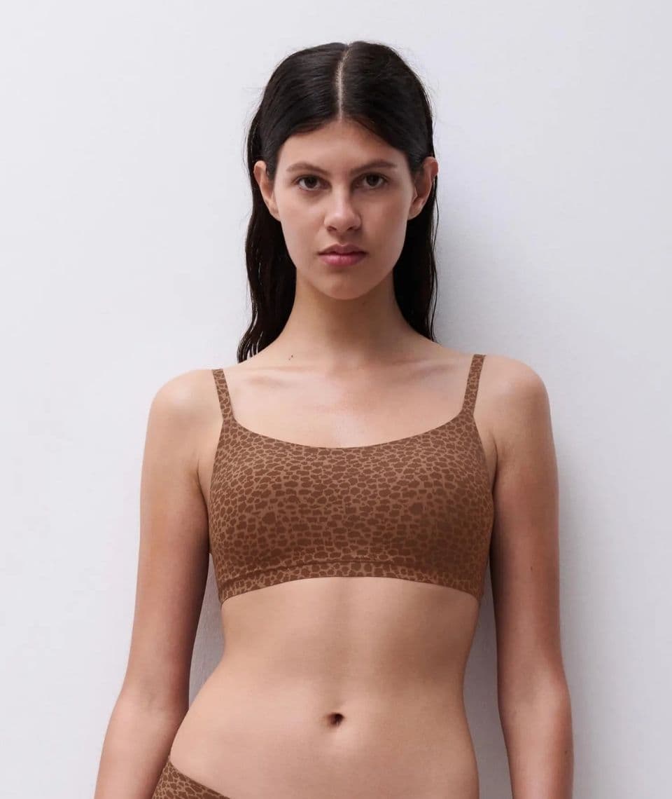 Woman in a brown leopard-print bra standing against a plain white background.