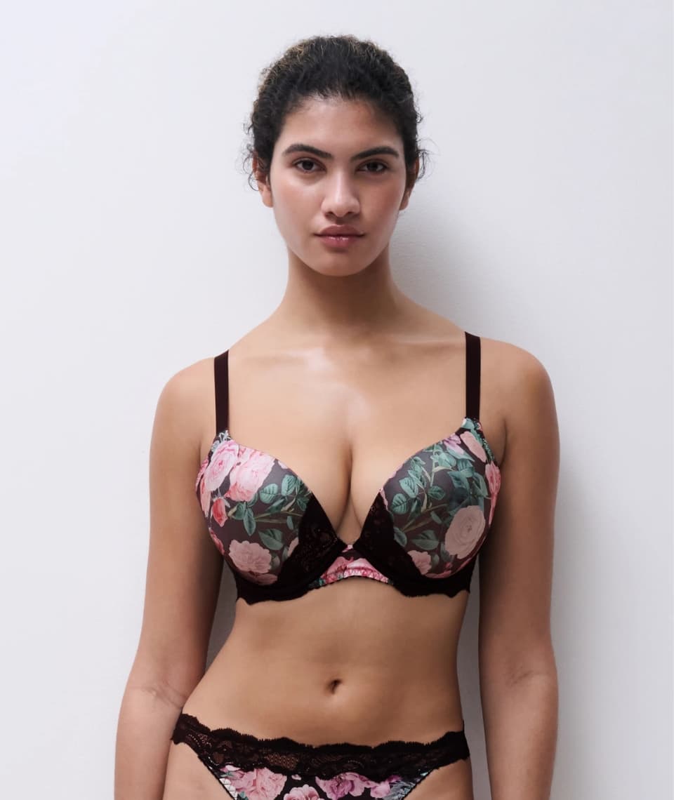 Person wearing floral lingerie with black lace details, standing against a plain white background.