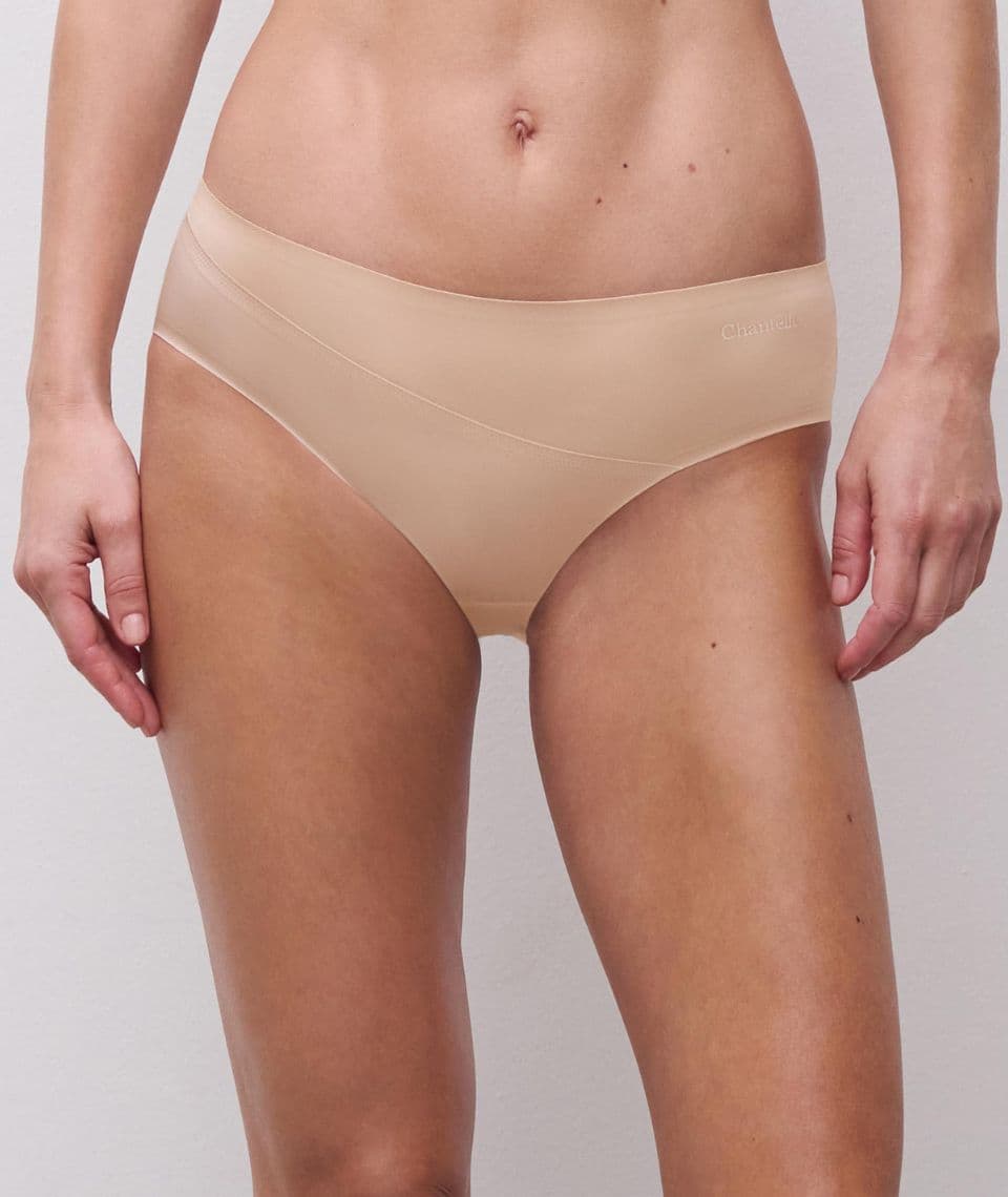 Person wearing seamless beige underwear, standing against a plain background.