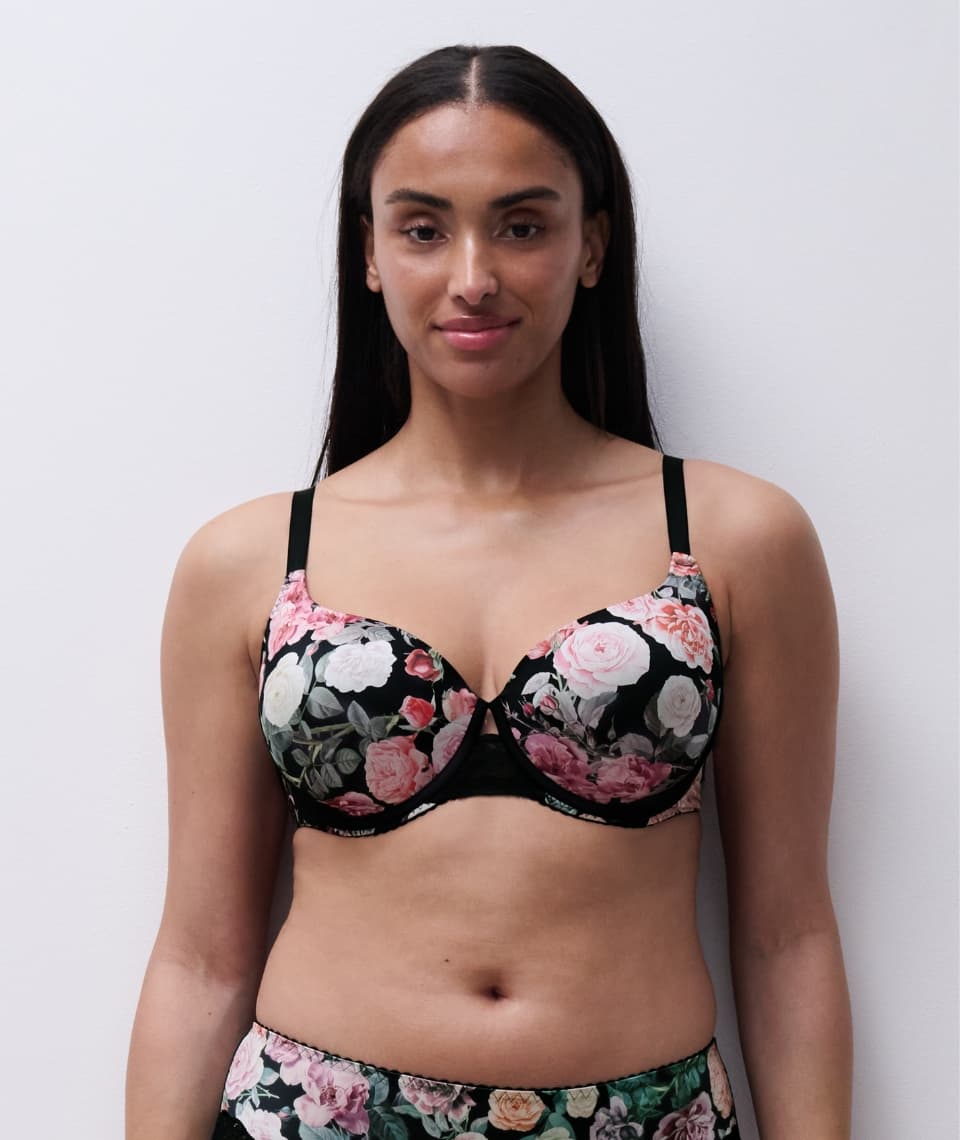 Woman wearing a black floral bra and matching bottoms, standing against a plain white background.