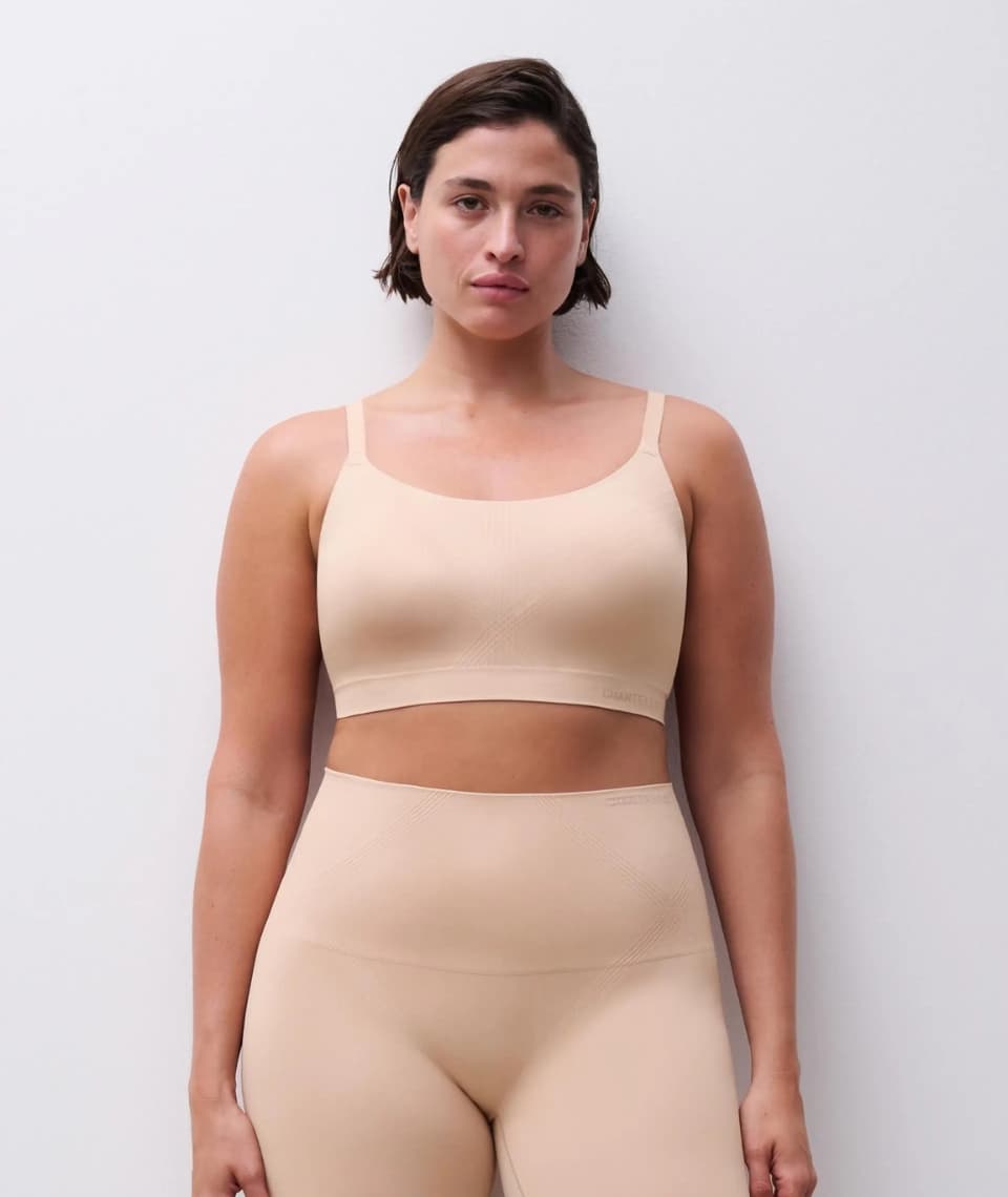Woman wearing a beige seamless bra and high-waisted leggings against a plain white background.