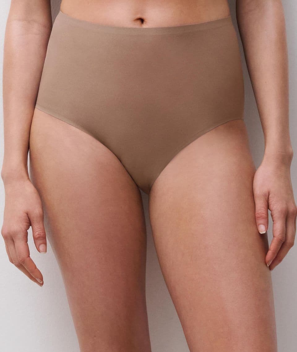 Person wearing high-waisted, seamless, brown underwear, showcasing a simple and smooth design against a plain background.