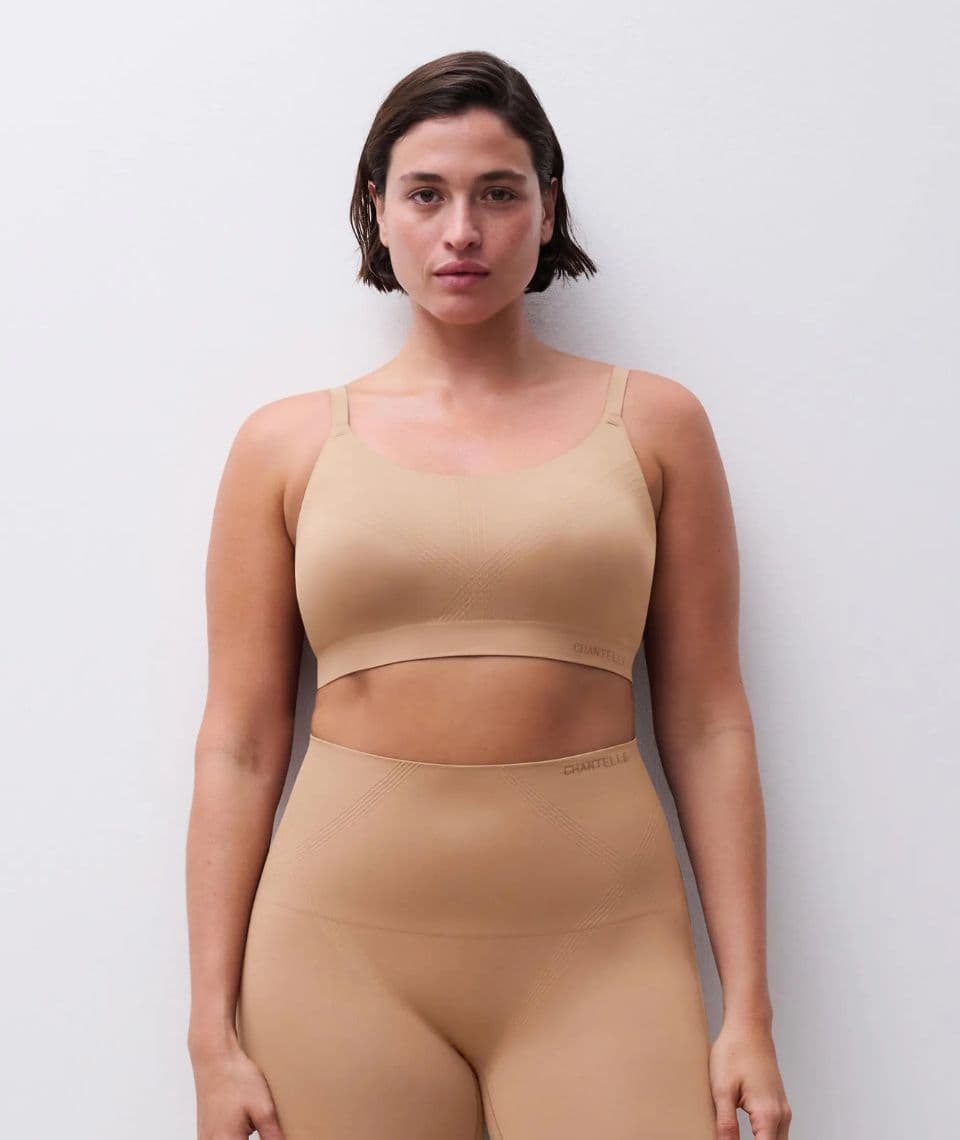 Person in beige, seamless activewear set against a plain white background, standing with a neutral expression.