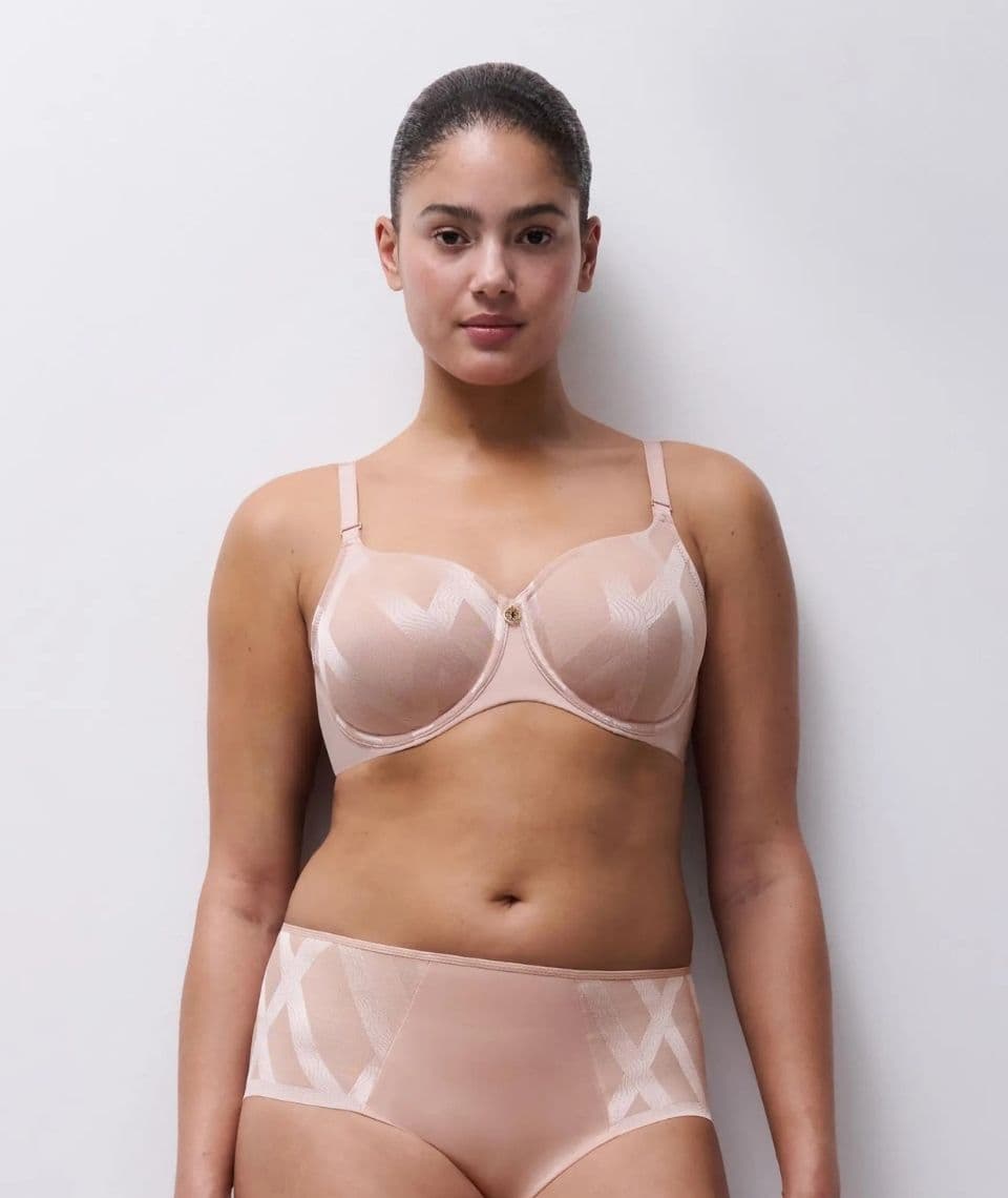 Person wearing a soft pink bra and underwear set with geometric patterns, standing against a plain white background.