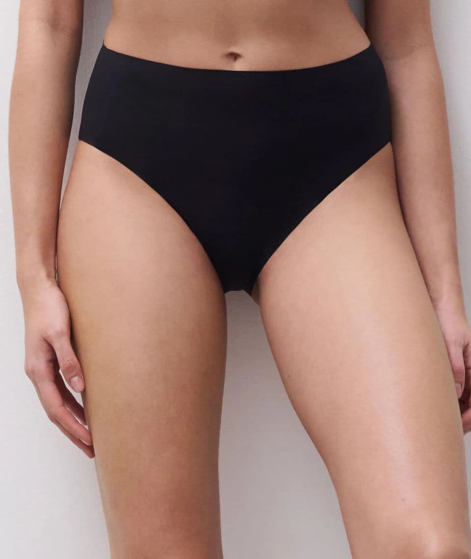 Person wearing high-waisted black underwear against a light gray background.