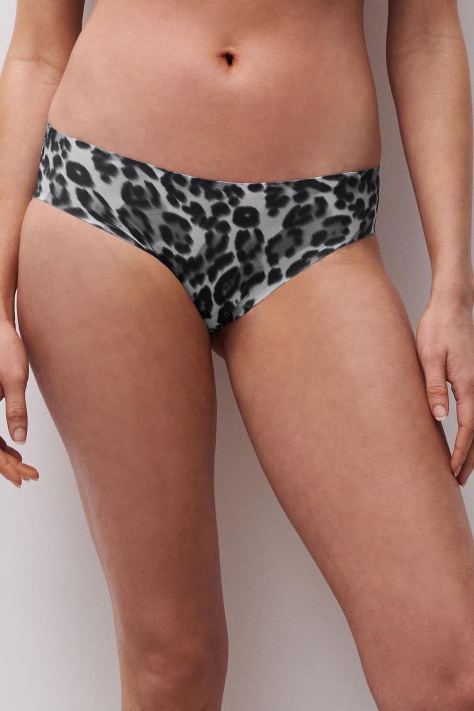 A person wearing leopard-print bikini bottoms stands against a plain background.