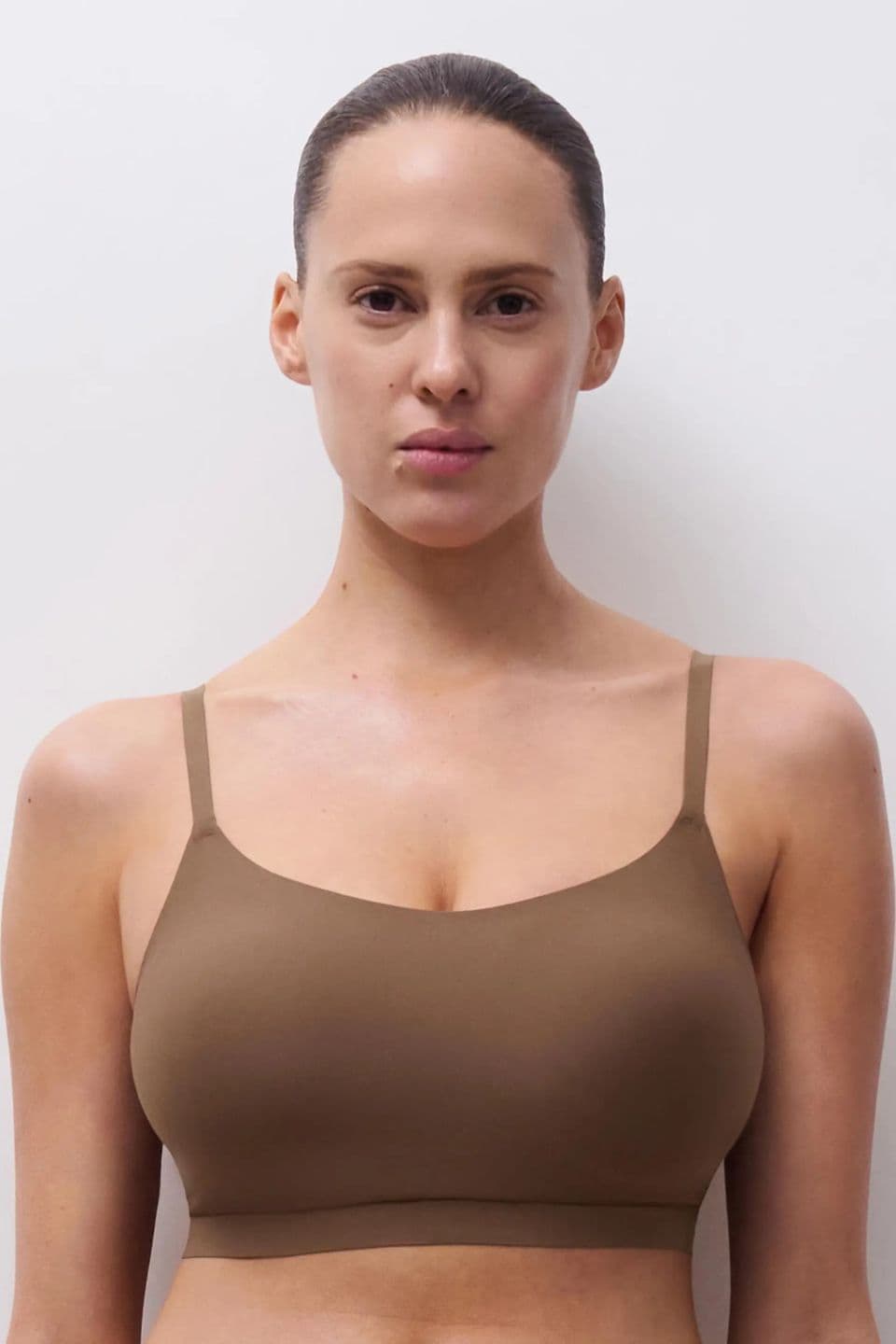 The image shows a woman wearing a brown seamless bra with thin straps.