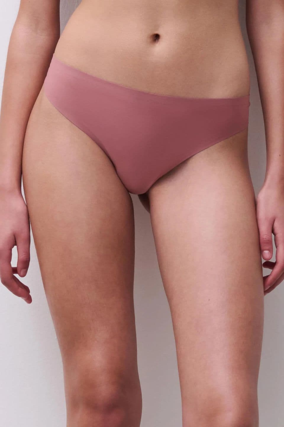A person's torso is shown wearing mauve hipster briefs, standing against a neutral background.