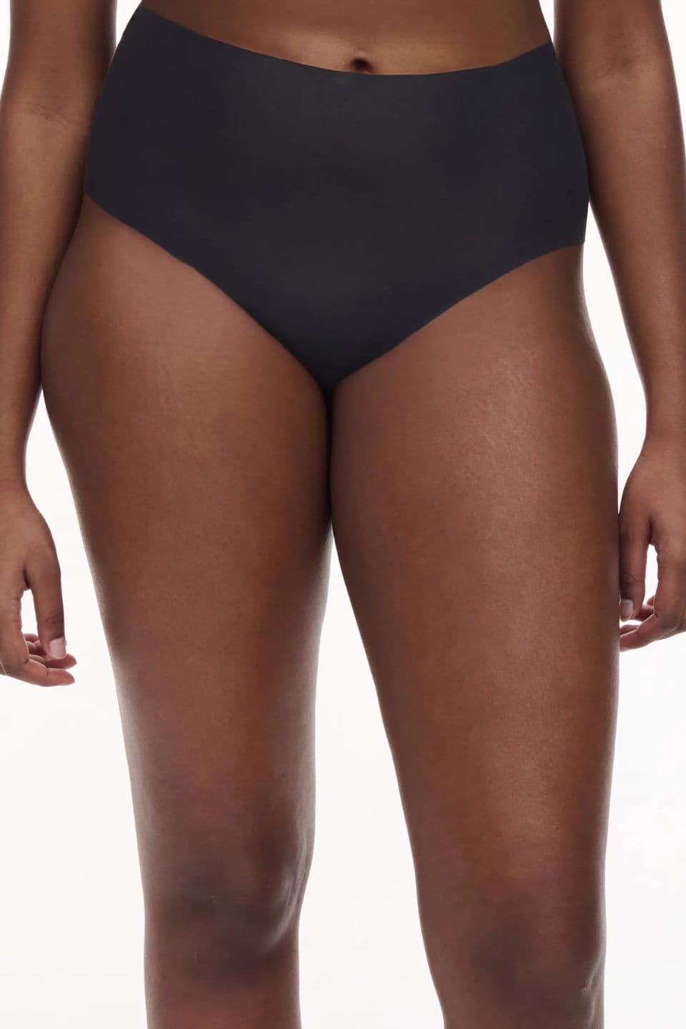 The image shows a close-up of a woman wearing a black seamless high-waist brief with a smooth, invisible finish.