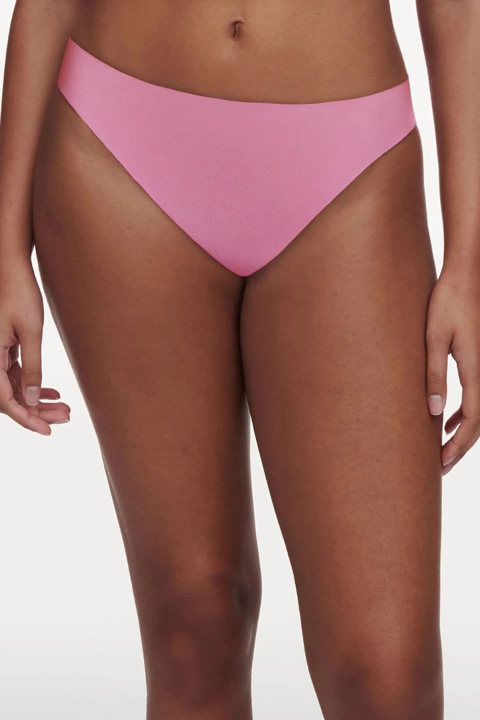 The image shows a close-up of a woman wearing a pink seamless thong with a smooth, invisible finish.