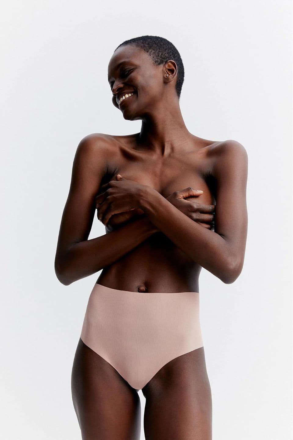 The image shows a woman wearing high-waisted seamless briefs in a nude tone.