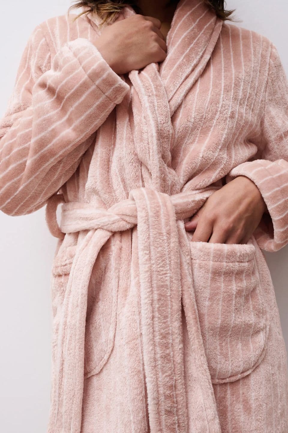 A woman wears a soft textured bathrobe in blush pink