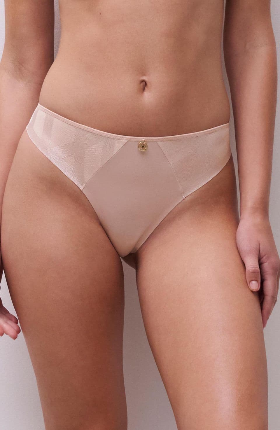 A person wearing nude-colored underwear with a small button detail on the front, standing against a plain white background.