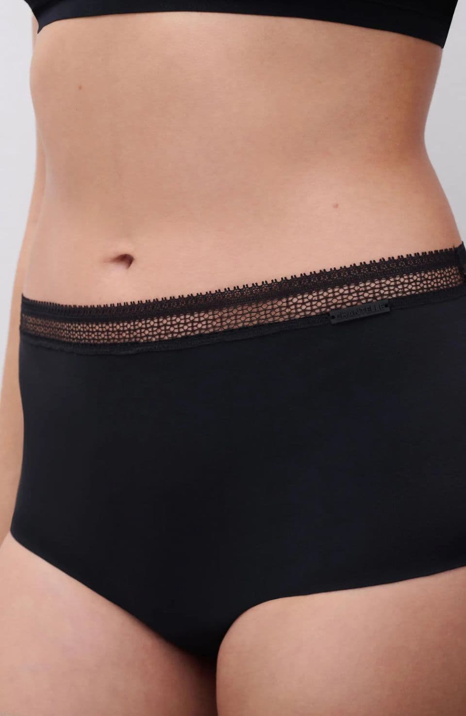Person wearing black high-waisted underwear with lace trim.