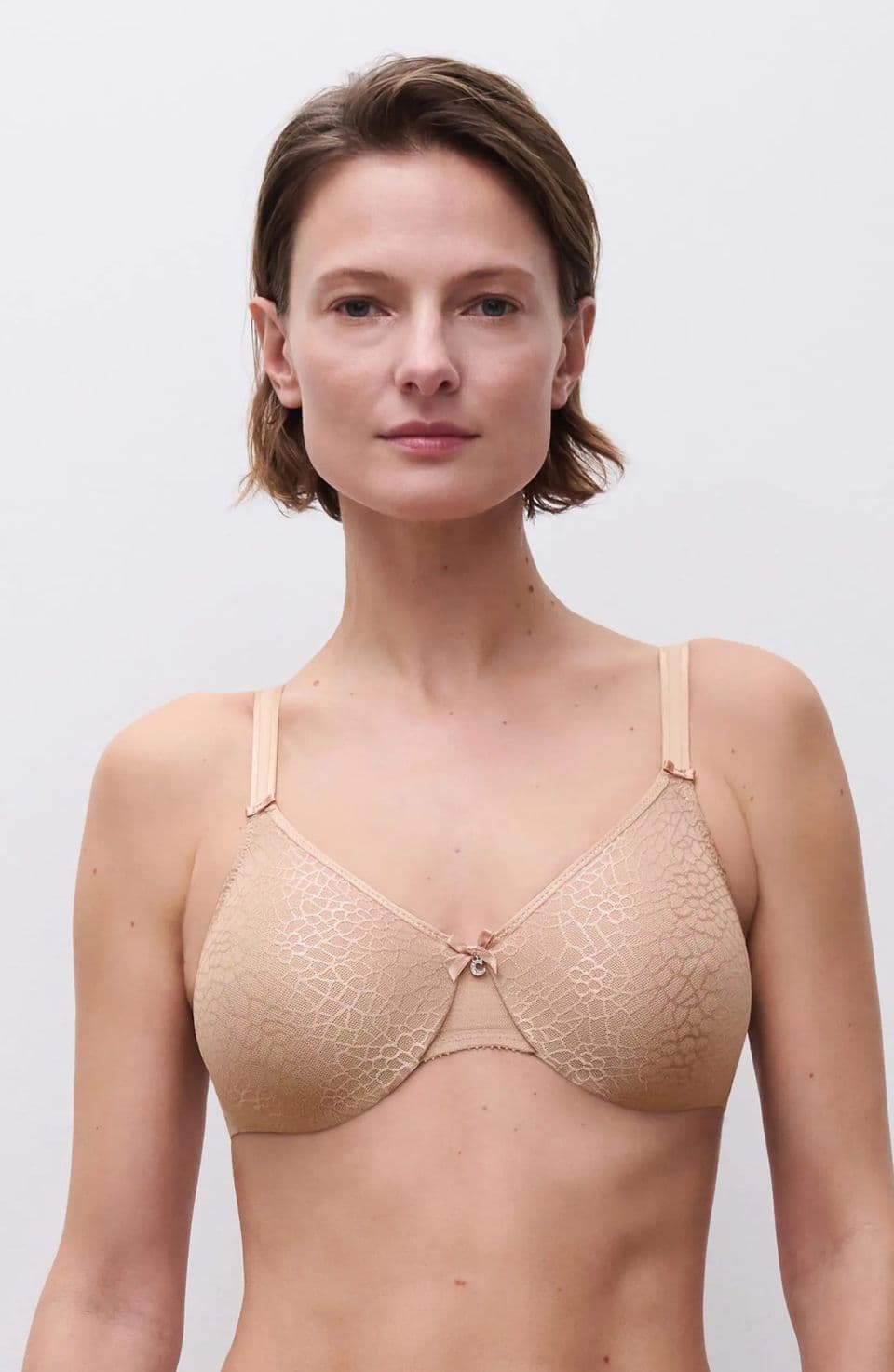 Person wearing a beige textured bra with thin straps, standing against a plain white background.