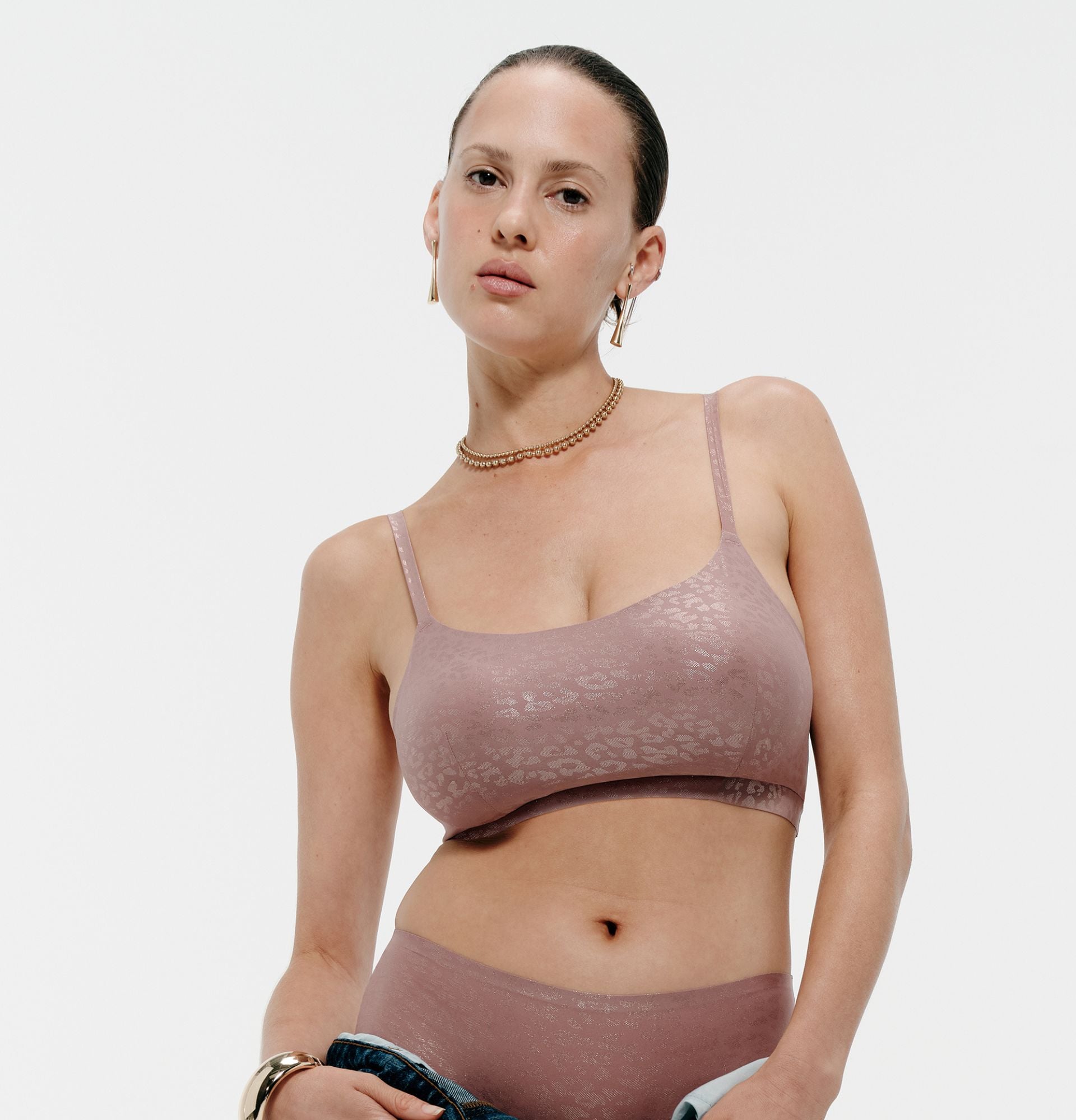 A woman is shown wearing a mauve seamless bralette and matching bottoms with a subtle shimmering leopard pattern.