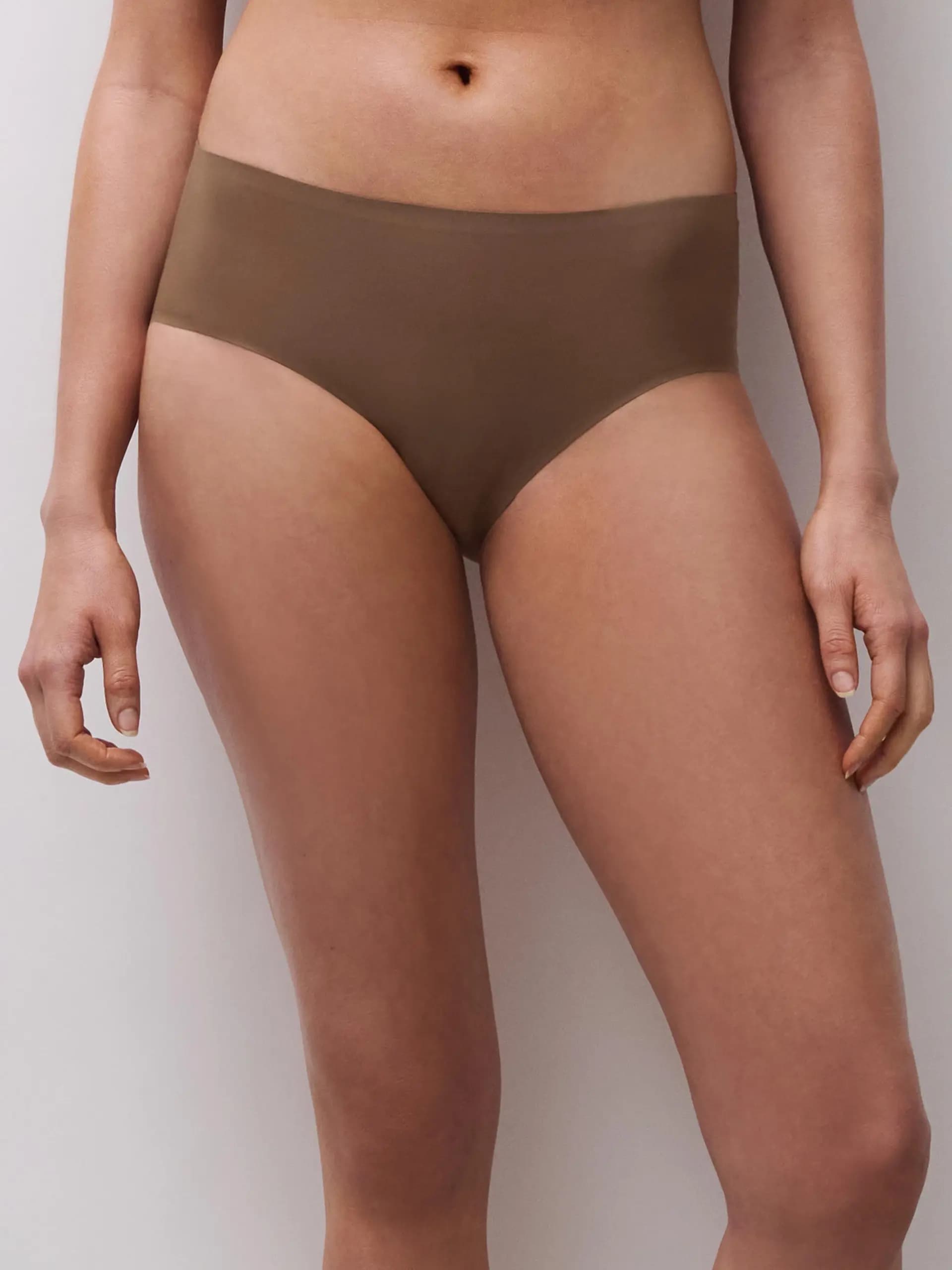Person wearing seamless, high-waisted brown underwear, standing against a white background.