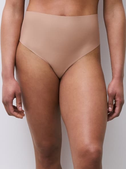 Close-up of a person wearing seamless, high-waisted nude-colored underwear against a neutral background.