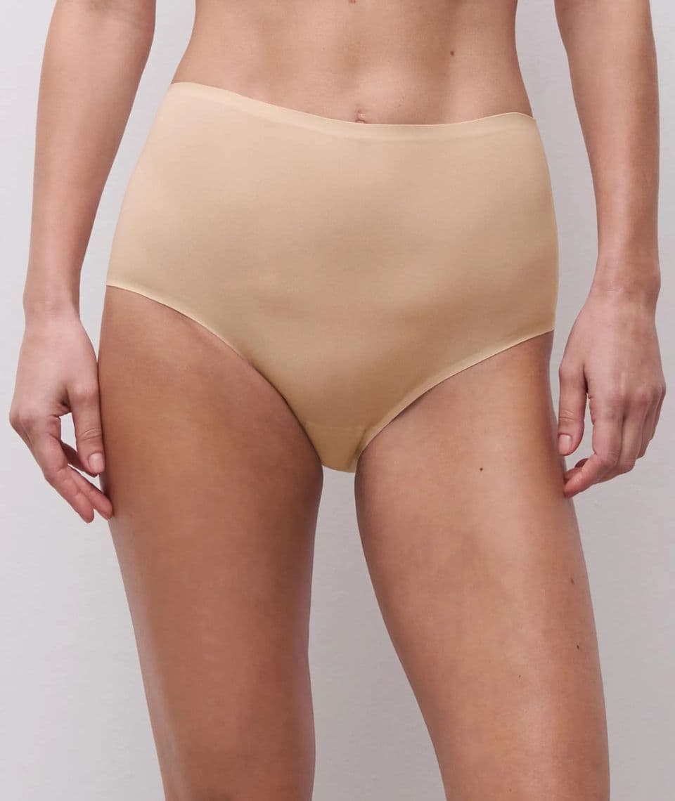 Person wearing high-waisted, seamless nude underwear, standing against a light gray background.