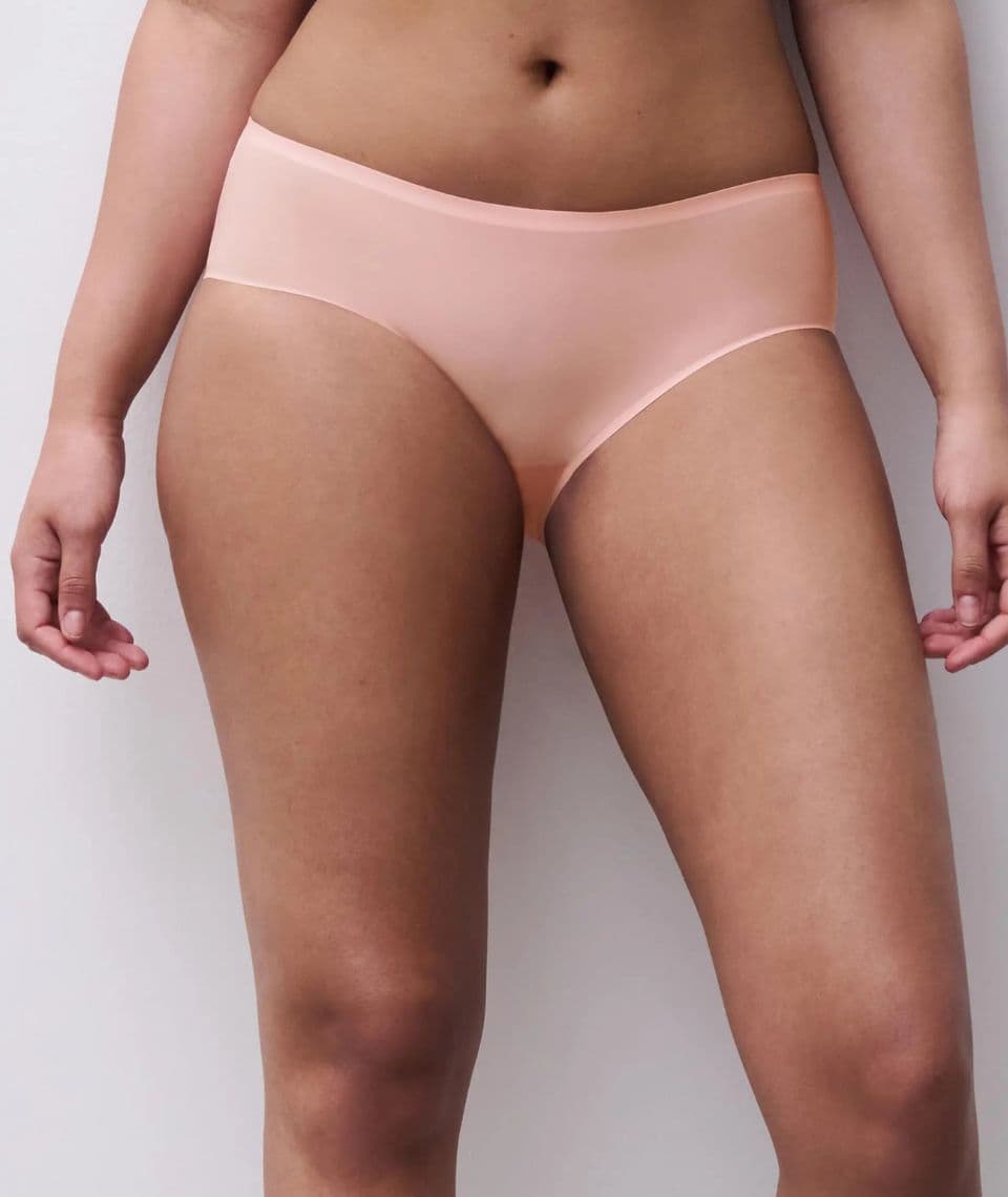 Person wearing a light pink-colored underwear against a plain background, focusing on the waist and upper thighs.